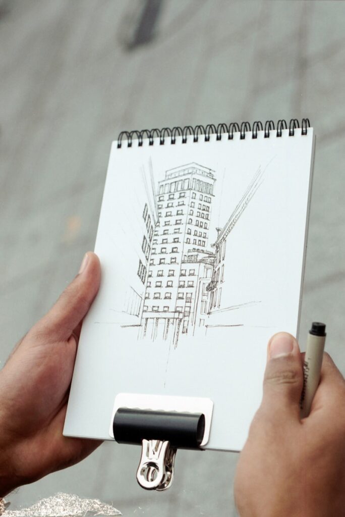person holding white notebook with black pen