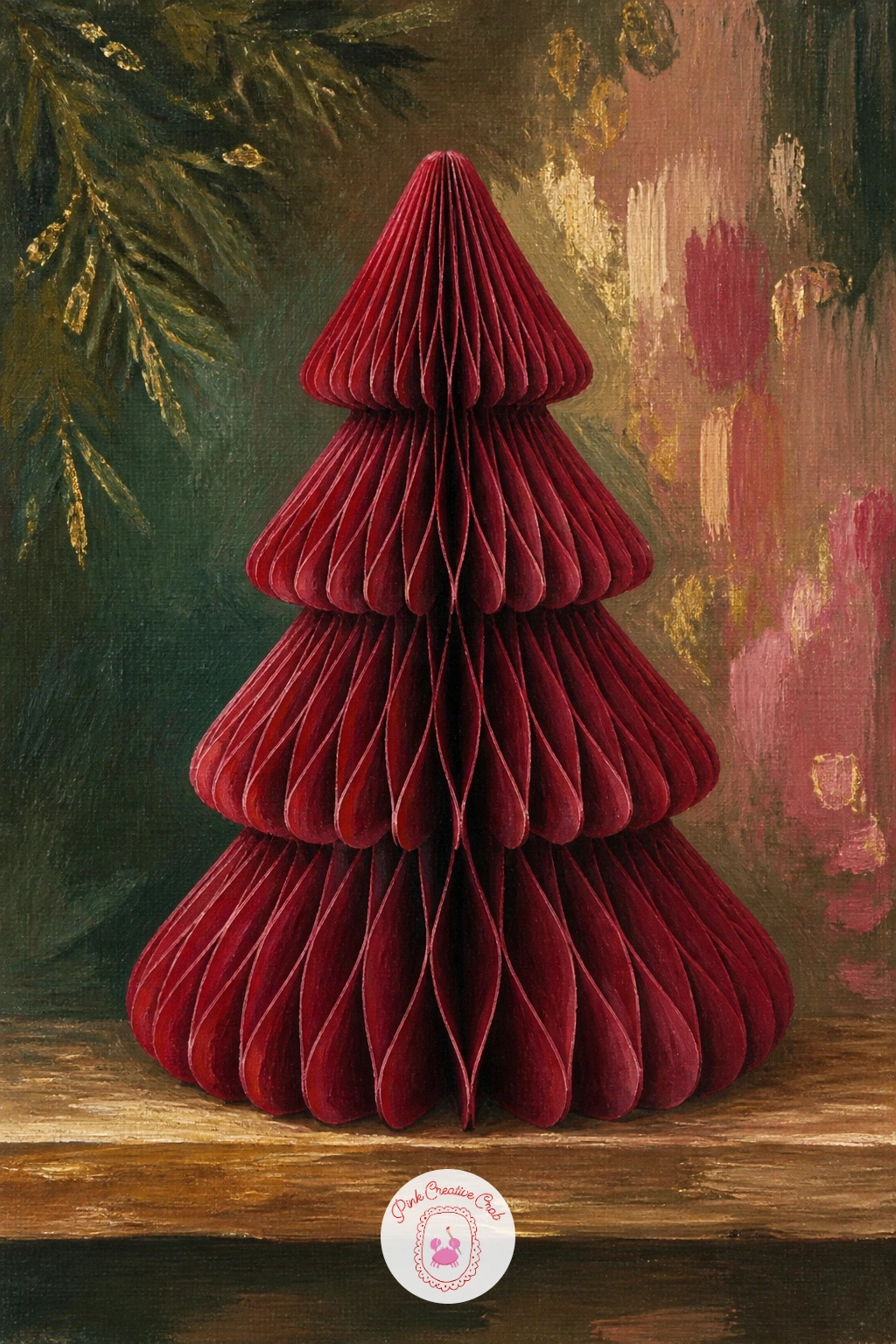 Honeycomb Paper Tree In Berry Red — Move from soft tinsel to something more graphic with a honeycomb paper tree in berry red, sitting on a simple wooden shelf.
