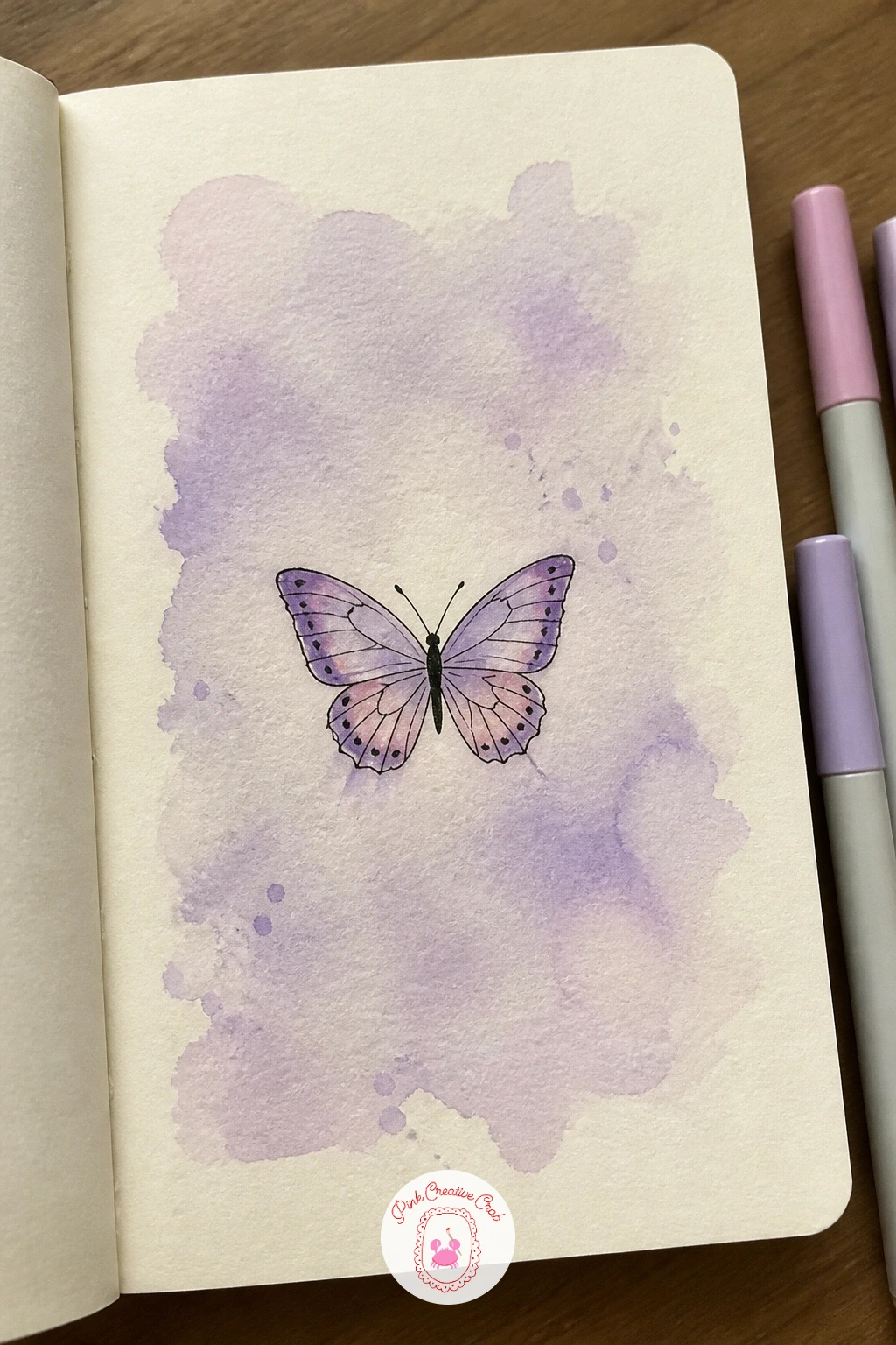 Lavender Wash Butterfly — Brush a loose lavender wash across the page in soft overlapping strokes, letting some areas dry paler than others so the color has